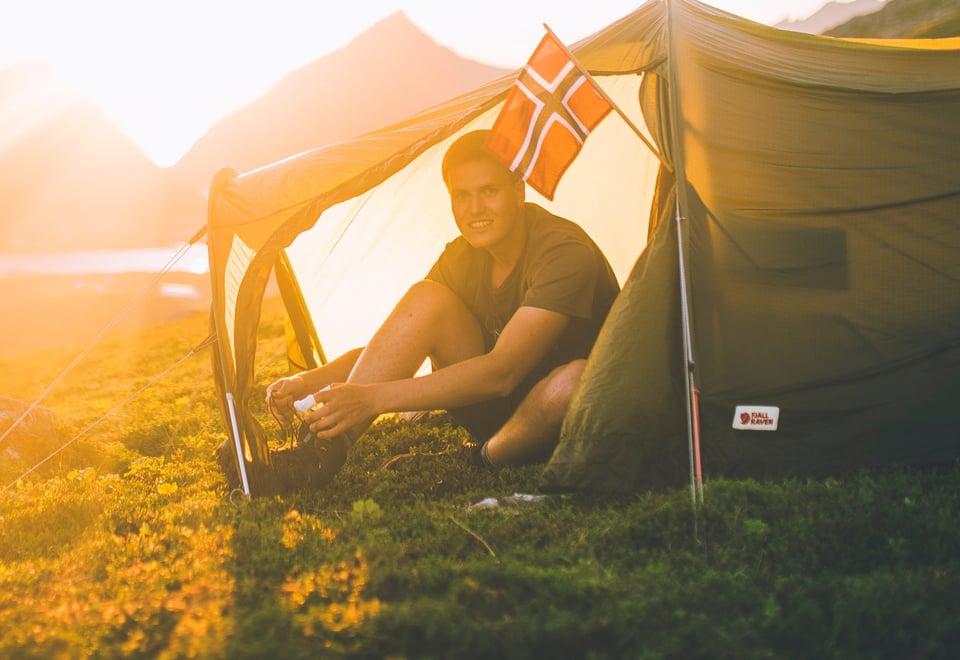 Mann i teltåpning i solnedgang