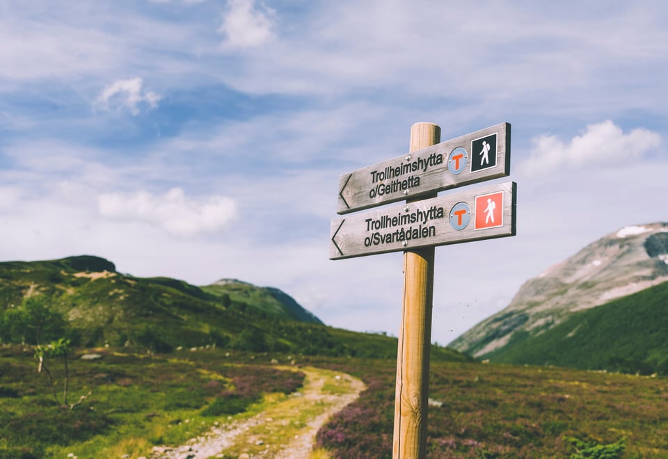 Skilt som viser mot en sti innover fjellet