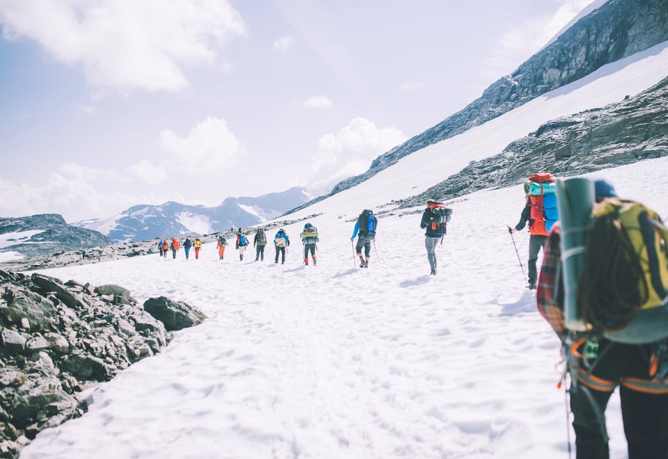 Personer som går på rekke over en isbre