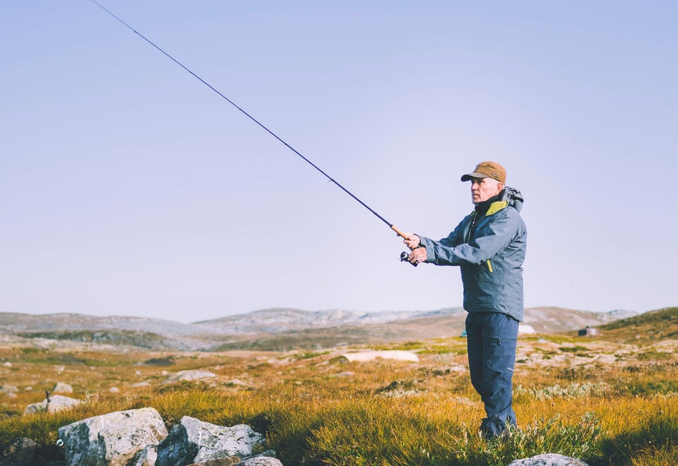 Mann med fiskestang i fjellandskap