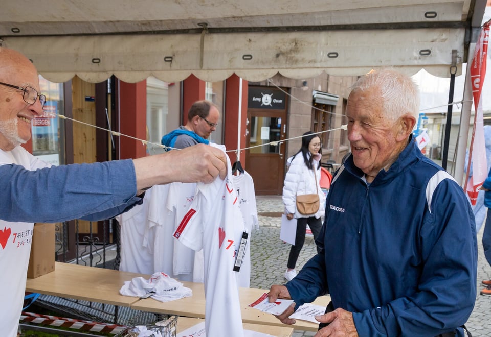 En senior deler ut en hvit t-skjorte til en annen senior.
