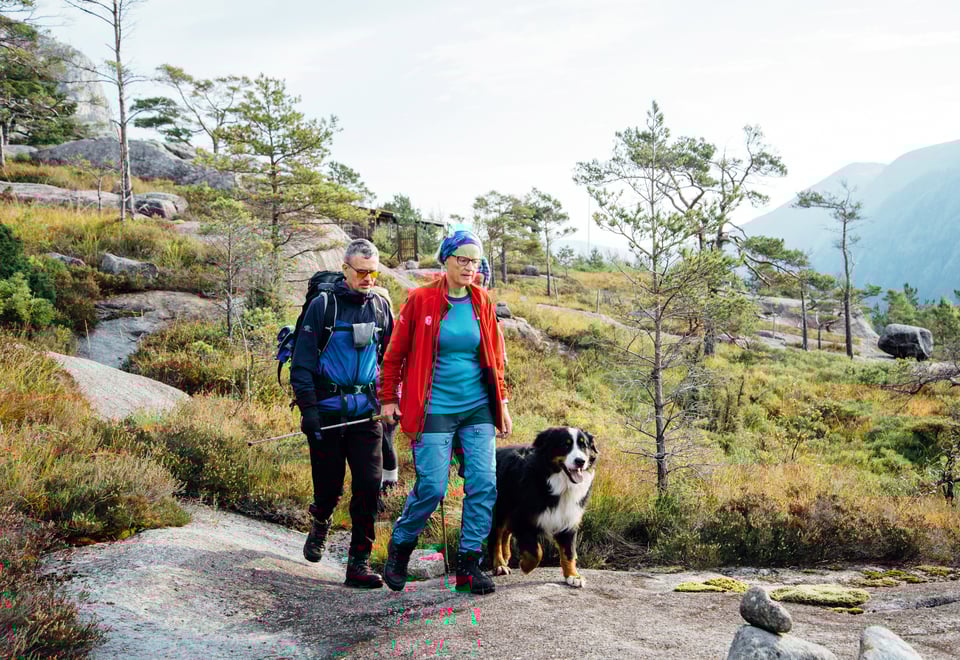 En mann går tur sammen med en dame som har gåstav og hund