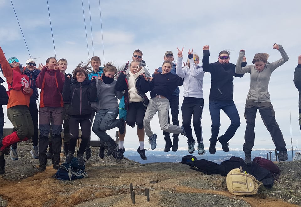 En gjeng med unge frillige som står på en fjelltopp, og alle hopper samtidig