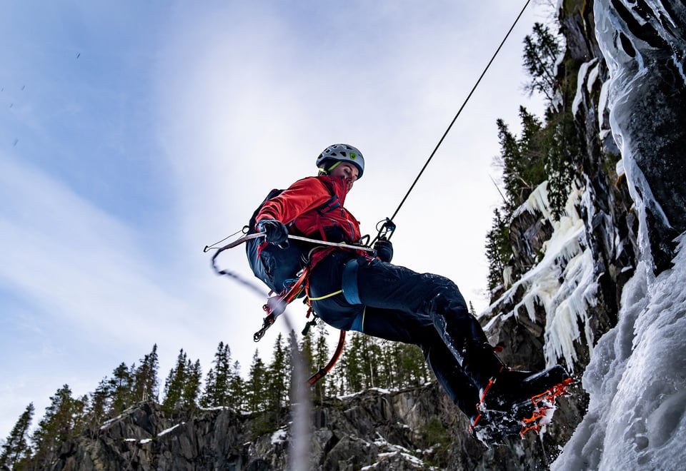 Isklatrer henger i tau ved frosset foss.
