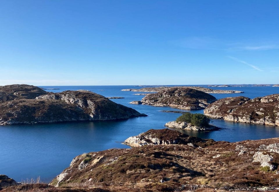 Bildet viser flere steinete svaberg som ligger rundt i havgapet foran oss, på en godværsdag.