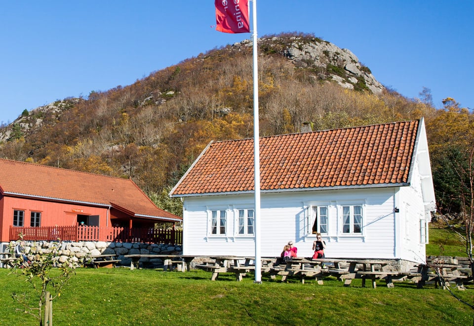 Hvitt hus og rød låve med et flagg som veiver i vinden.
