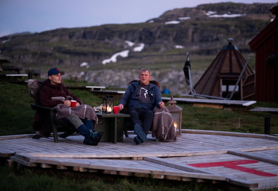 To menn sitter i hver sin stol utendørs i kveldsola.