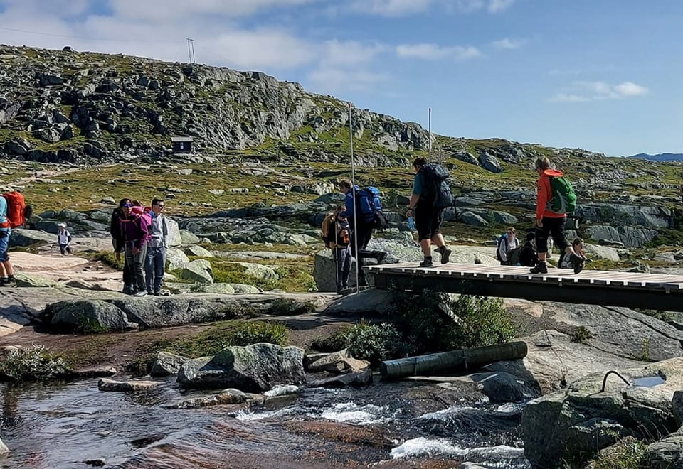 En gruppe mennesker går over en bro på fjellet. Foto.