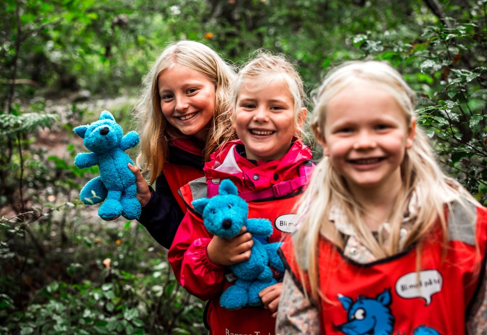 Tre jenter med lyst hår som ser i kamera og smiler. De holder hver sin turbobamse i hånden.
