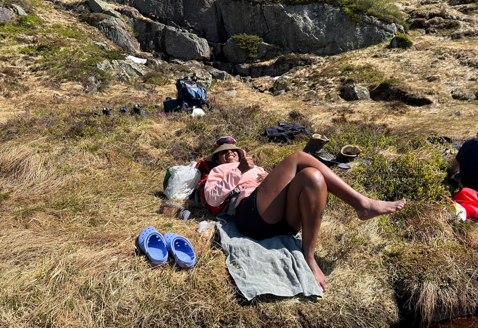 En dame ligger i gresset og soler seg.