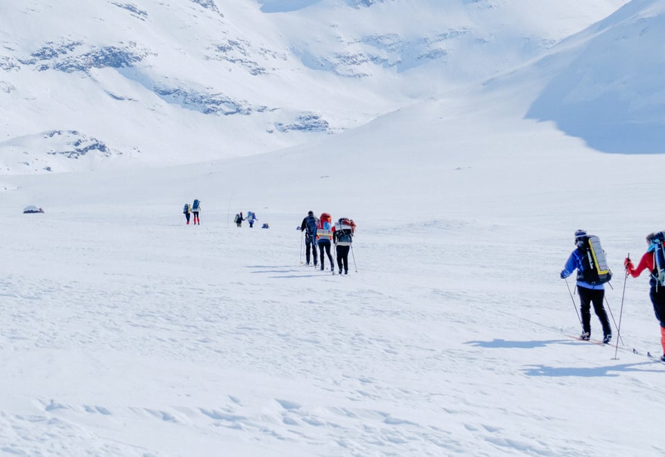 Personer som går på fjellski innover et vinterdekket fjellandskap
