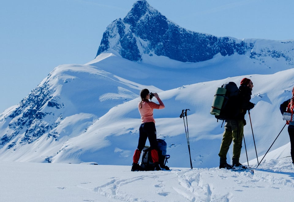 Tre personer på ski som ser utover et snødekket landskap