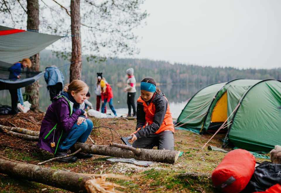 To jenter som sager ved på leirplass. 