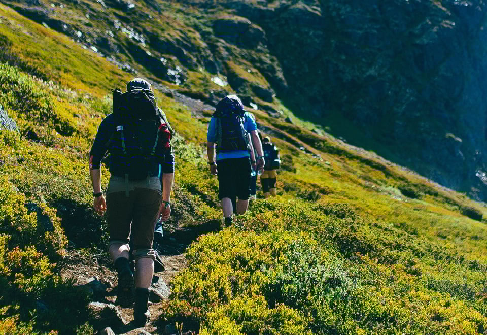Tre personer med sekk som går på en sti