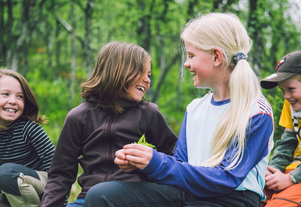 Fire barn som smiler og ler ute i skogen