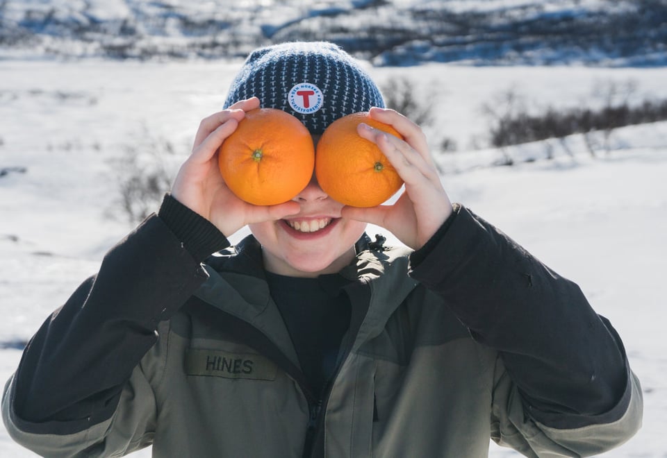 Gutt som holder to appelsiner foran ansiktet