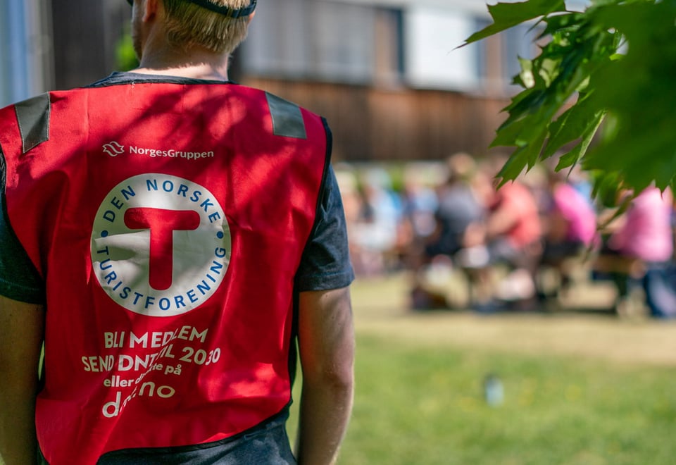 Mann med rød vest som står med ryggen til