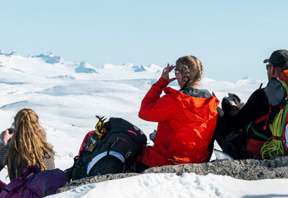 Tre personer som speider utover snødekte fjell