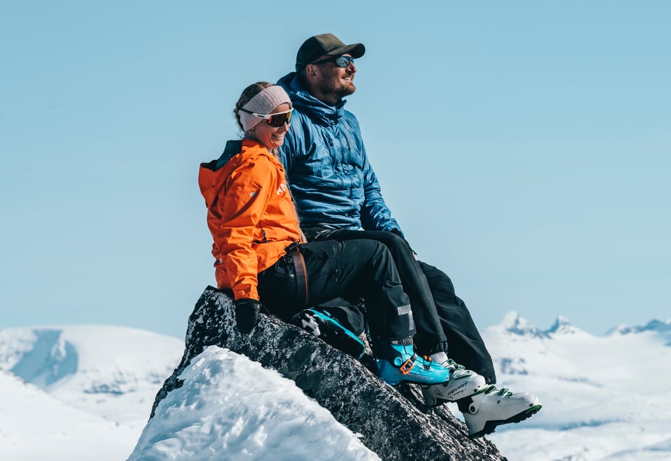 To personer som sitter på en fjelltopp med utsikt