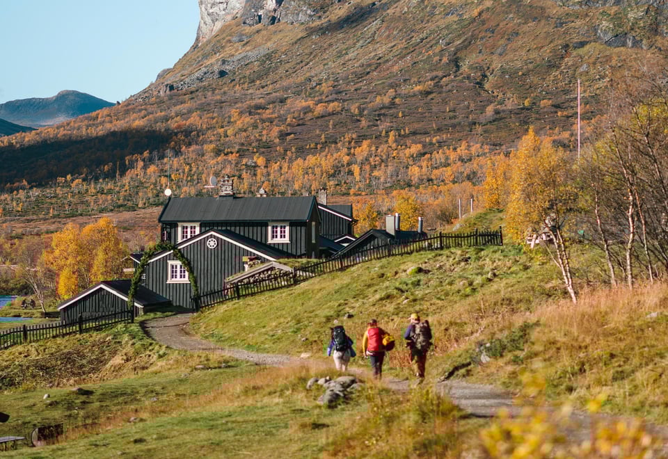Personer som går til en hytte i fjellet
