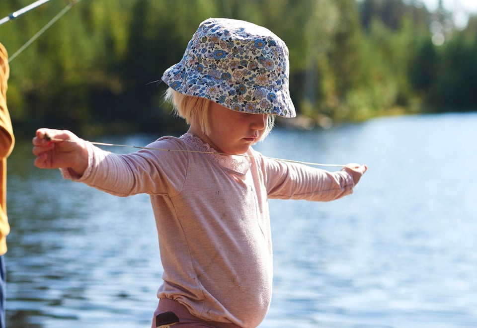 Barn med solhatt som balanserer på en stokk