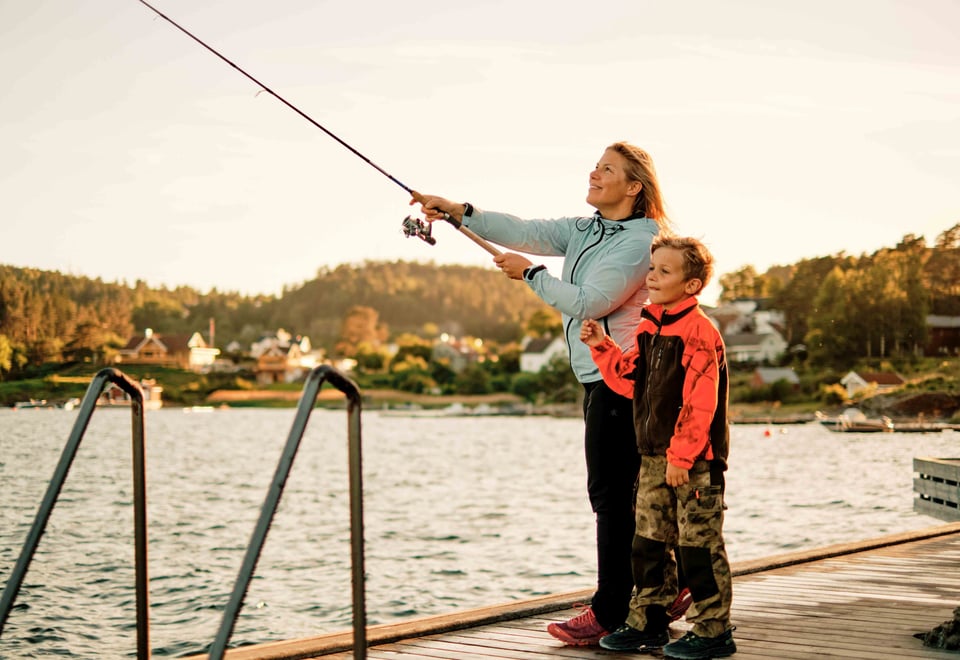 Dame og gutt fisker på brygge