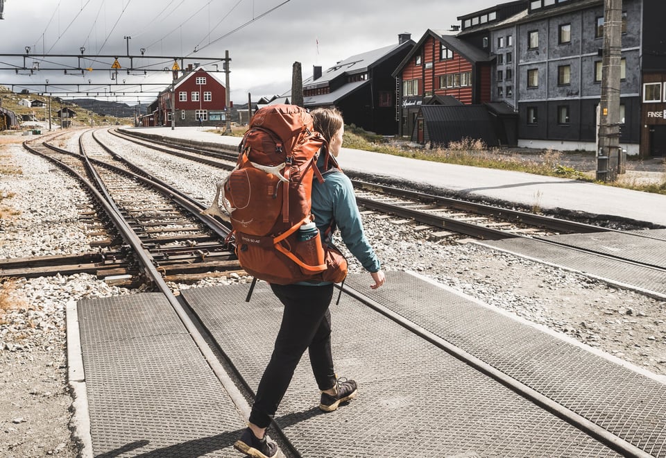 Person med ryggsekk som går over toglinjer.