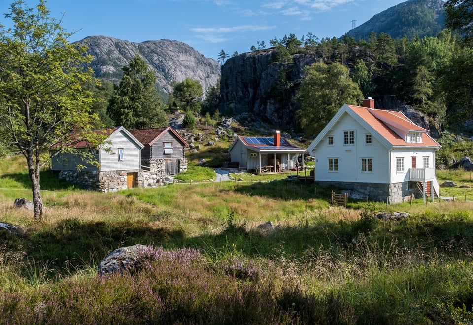 Bilde av tre bygninger som ligger i naturskjønne omgivelser.
