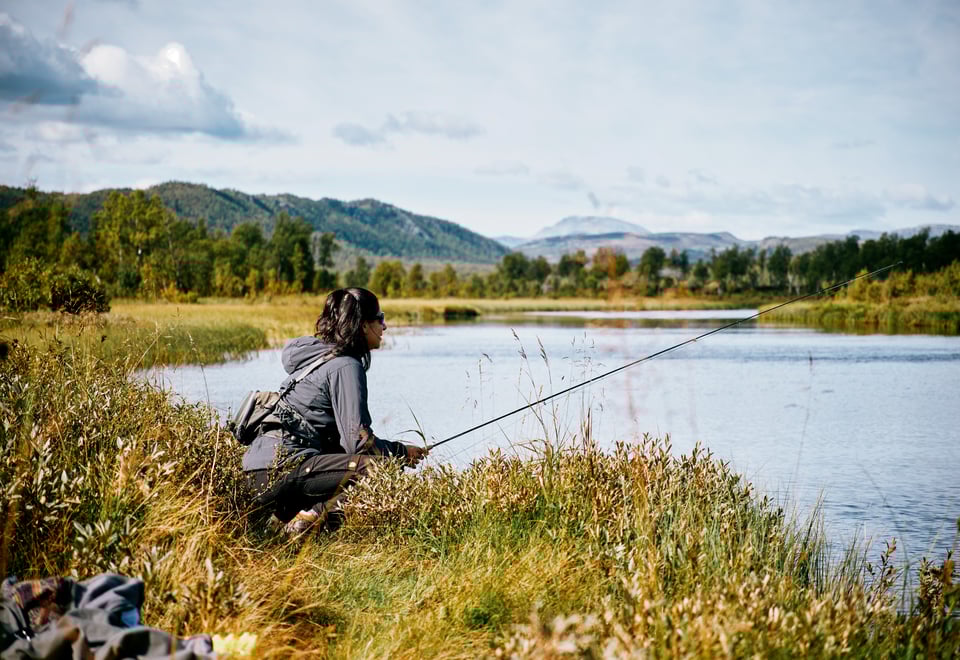 Kvinne med fiskestang i fjellandskap