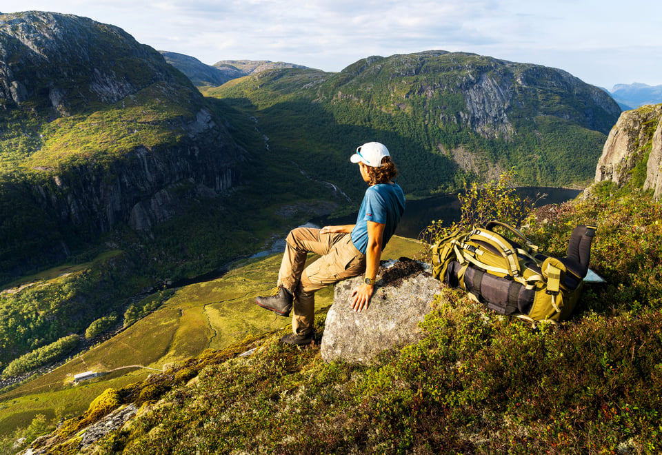 Mann sitter på stein med utsikt mot dal bak