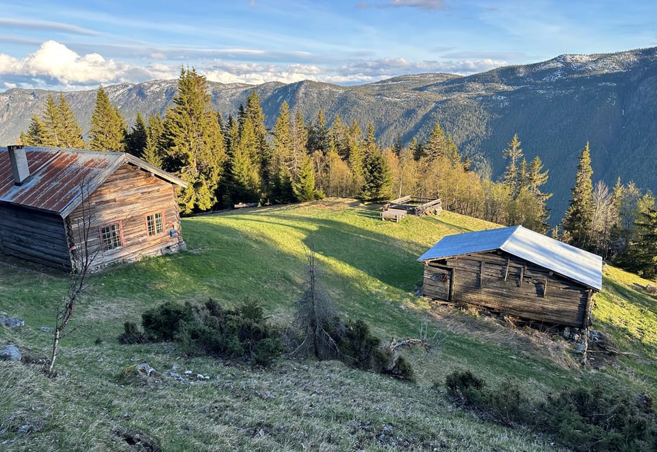 Gammel heigård på nordøstsiden av Bandak i Tokke kommune. Ser husene og fjellene på andre siden av Bandak