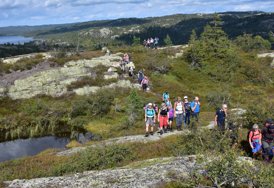 Innsjø og fjell på sommeren med en gruppe mennesker på tur