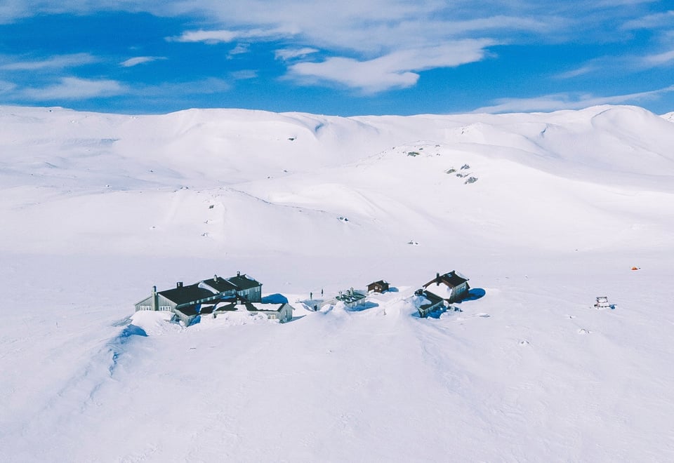 Flyfoto av en snødekket hytte i fjellet