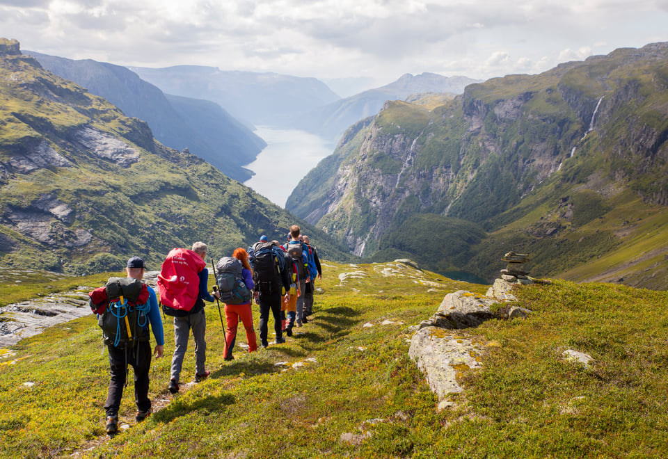 Turfølge går på sti på fjellet  med vakker vestlandsfjord i det fjerne
