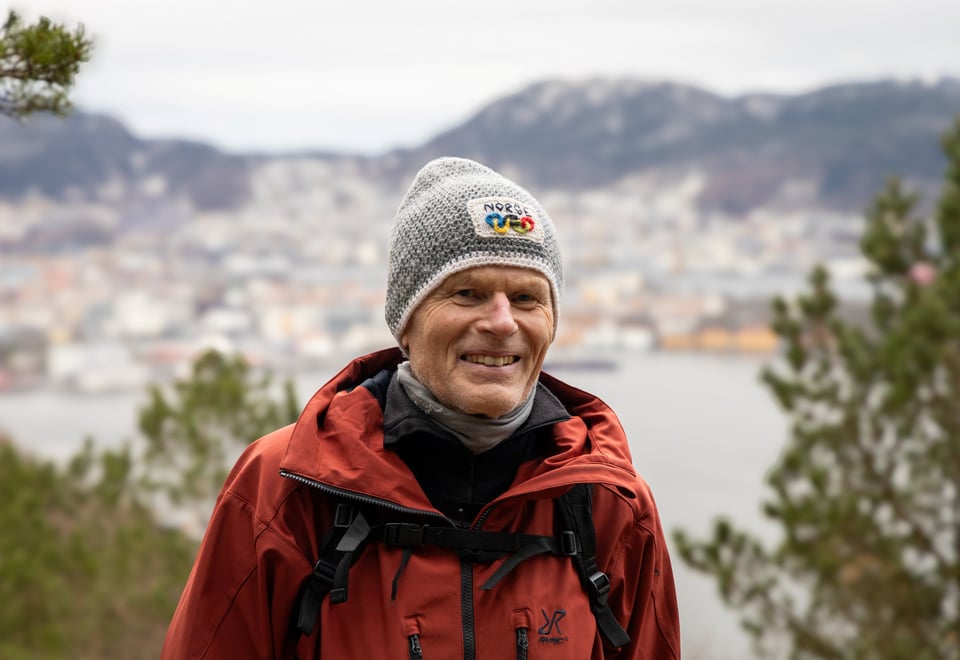 Mann med lue smiler på fjell.