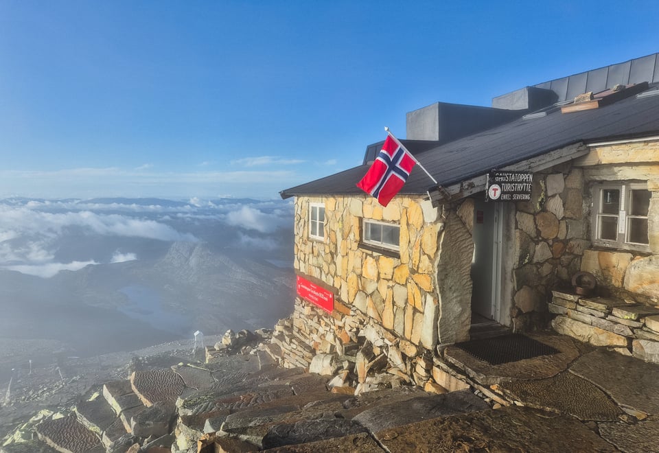 Stein, hytte, fjell og klar himmel