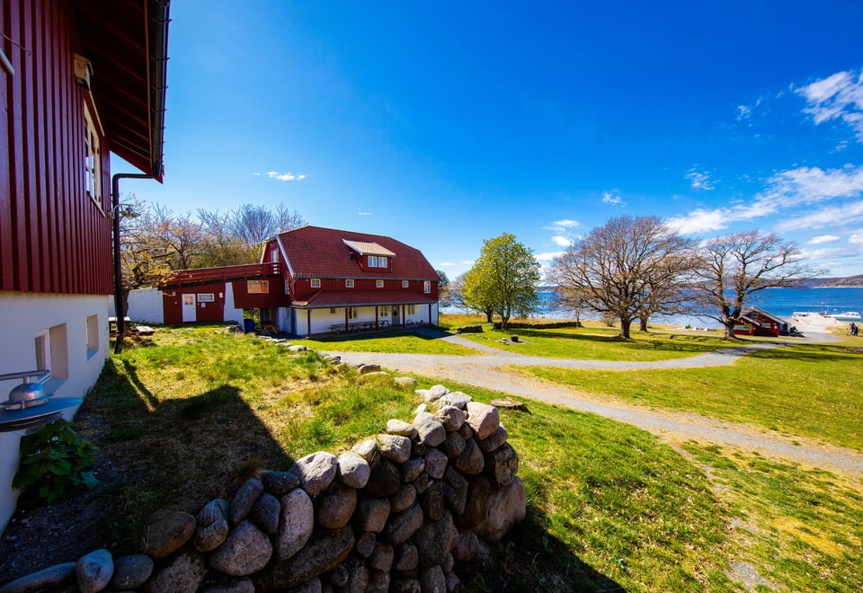 Blå himmel, grønt grass og boliger malt i rødt.