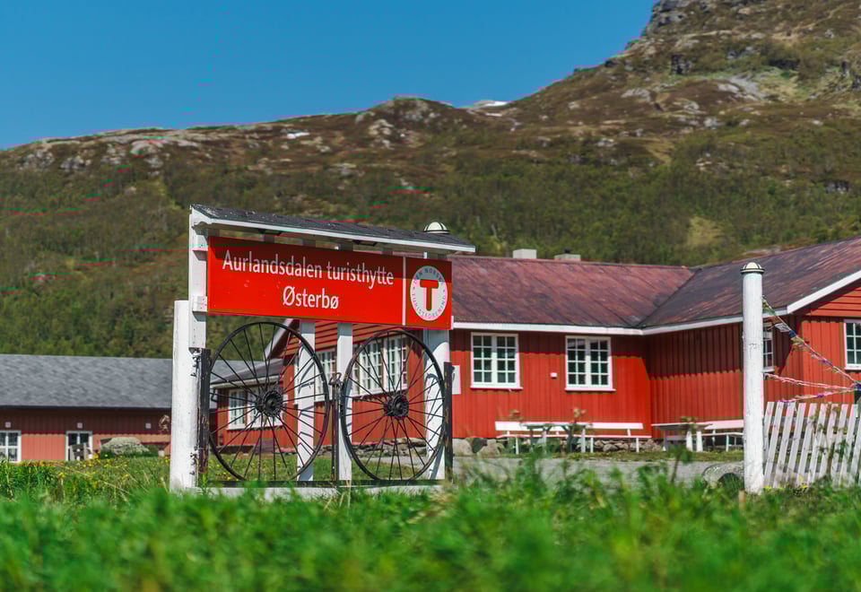En rødmalt hytte med et skilt hvor det står Aurlandsdalen Turisthytte foran