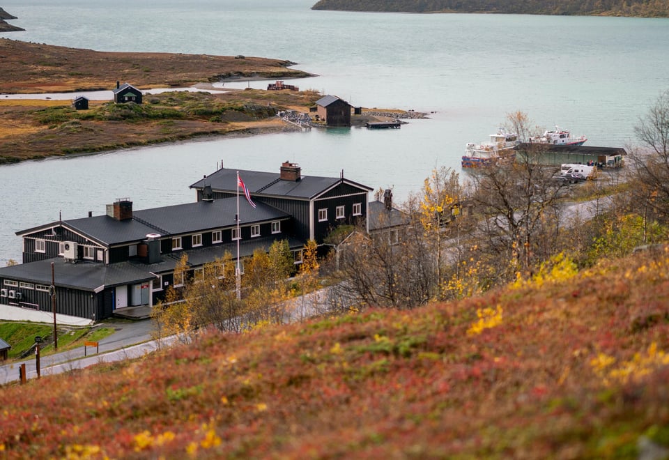 Høstfarger i fjellet rundt en svartmalt hytte 