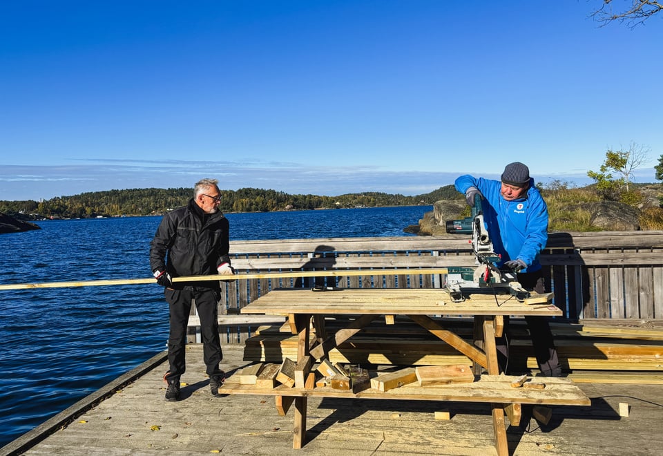 To mennesker snekrer på en benk, på en brygge. 