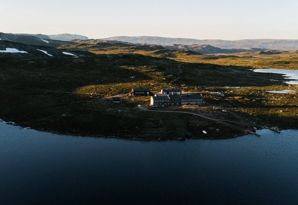 En hytte i solnedgang i et fjellandskap