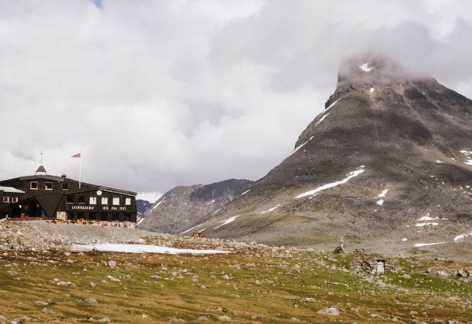 En fjellhytte i et sommerlandskap med et karakteristisk fjell i bakgrunnen
