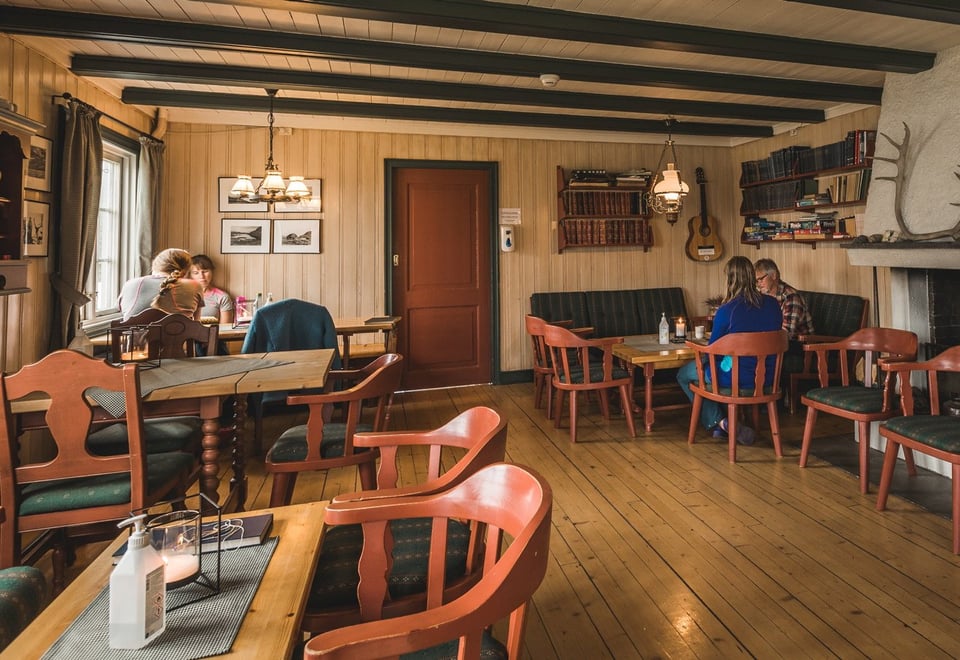 En eldre peisestue hvor 2 par sitter og koser seg inne på Iungsdalshytta i Skarvheimen