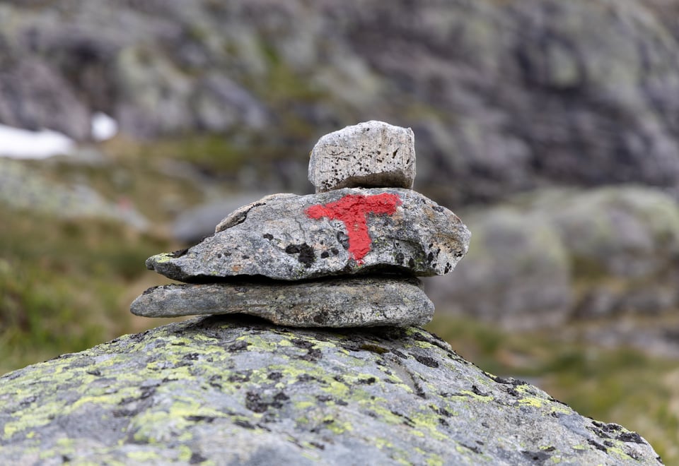 Rødmalt T på varde med tre steiner.