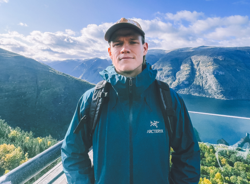 En mann med caps med fjell og vann i bakgrunnen