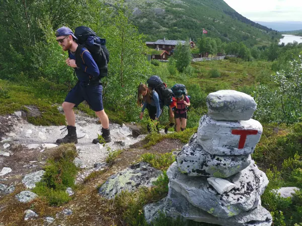 Ungdommer med turutstyr passerer en varde merket med rød T