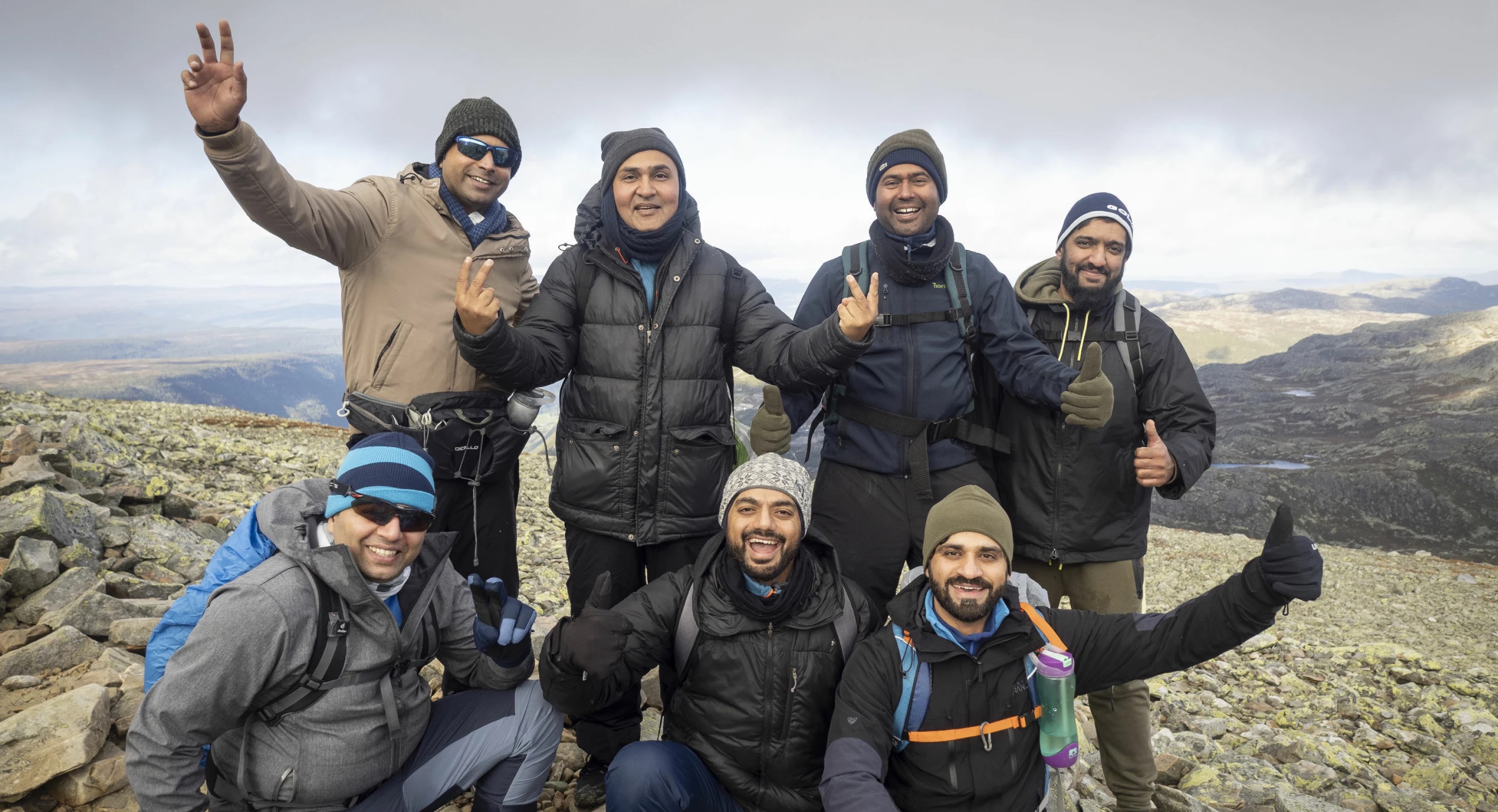 Gruppe menn smiler på toppen av fjell
