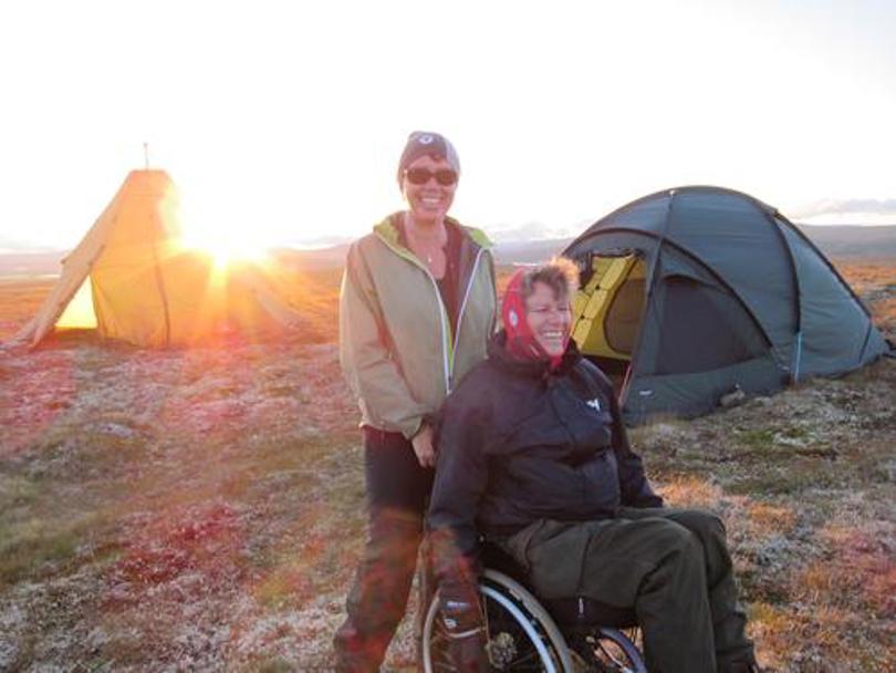 To glade mennesker utenfor teltene sine, ene i rullestol