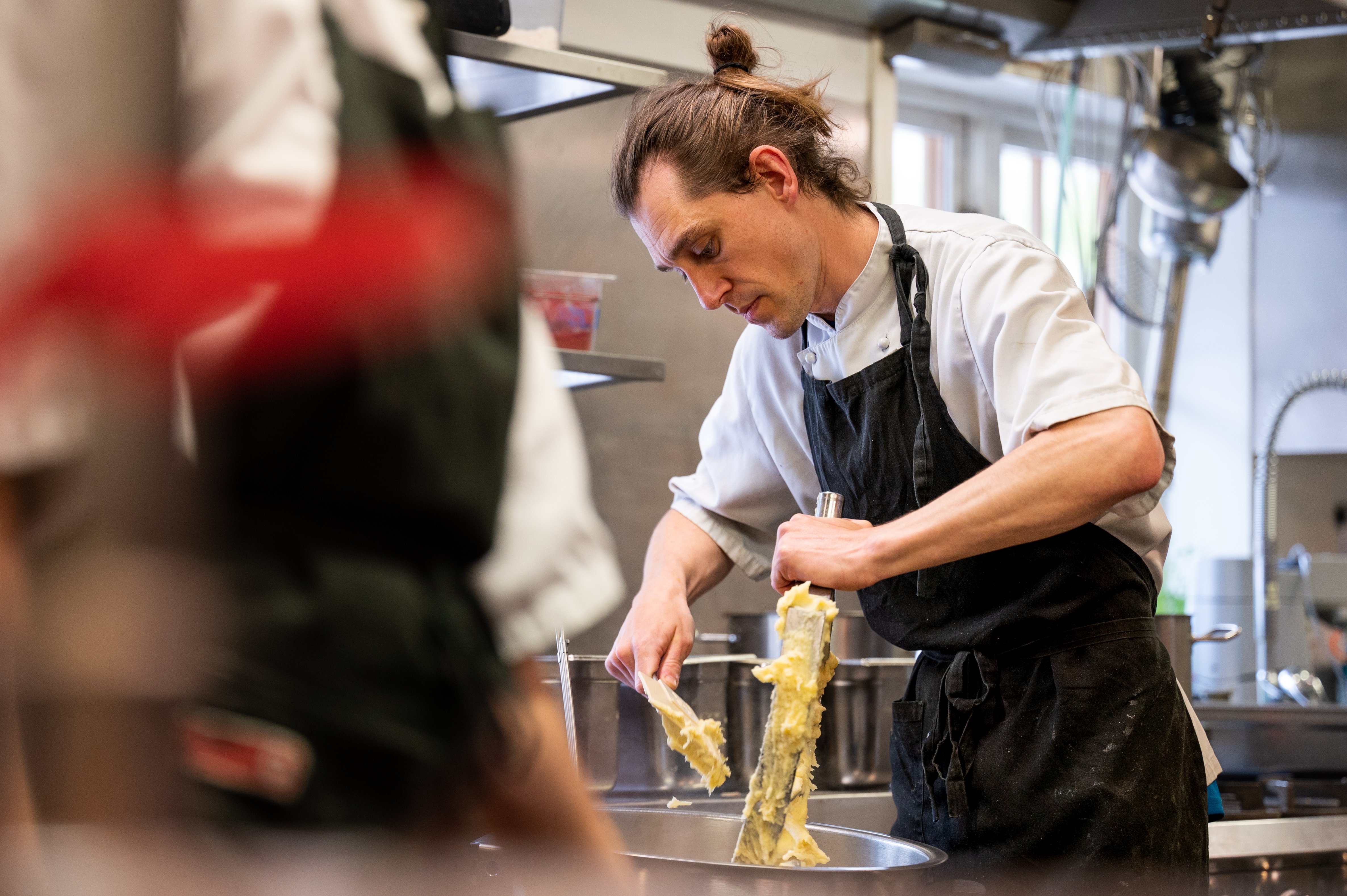 Foto. En mann med forkle jobber med en kjøkkenmaskin.