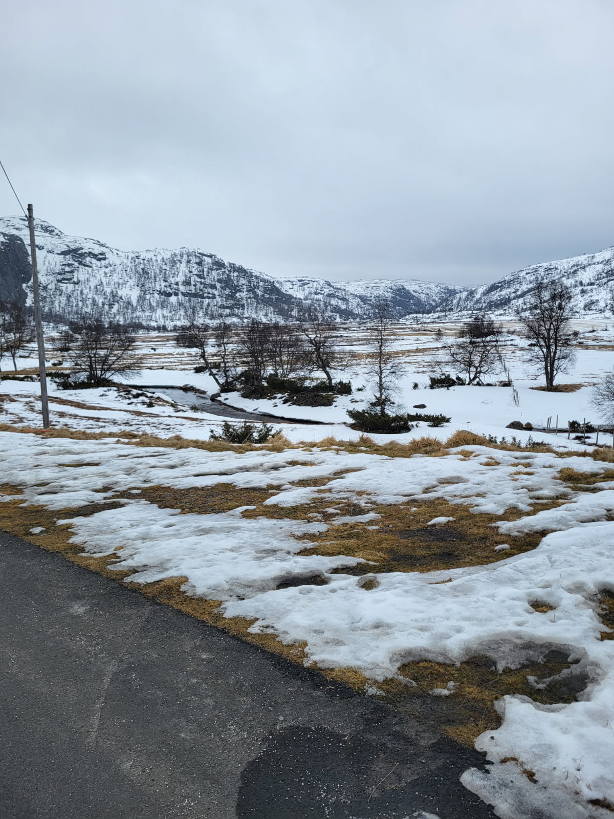 Lite sn&oslash; p&aring; bakken i et fjellandskap.